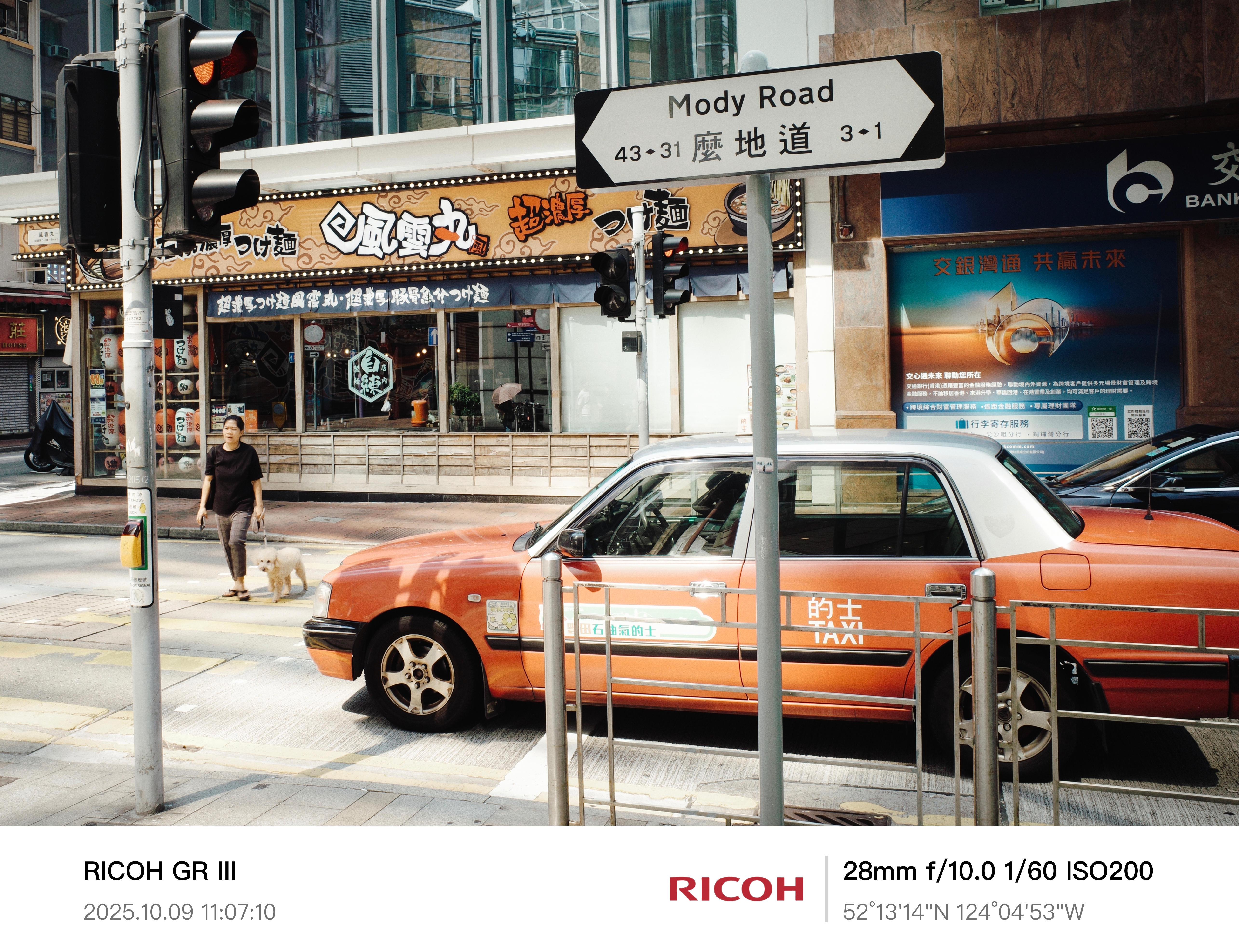 2025 - City in Motion - HK
《信號》
红灯、出租车、路牌、行人——城市的秩序精确如一台机器。
一个人牵着狗穿过马路，阳光打在橙色出租车上，闪着金属般的冷光。
表面的平静之下，是城市节奏中对方向、规则与意义的不断确认。