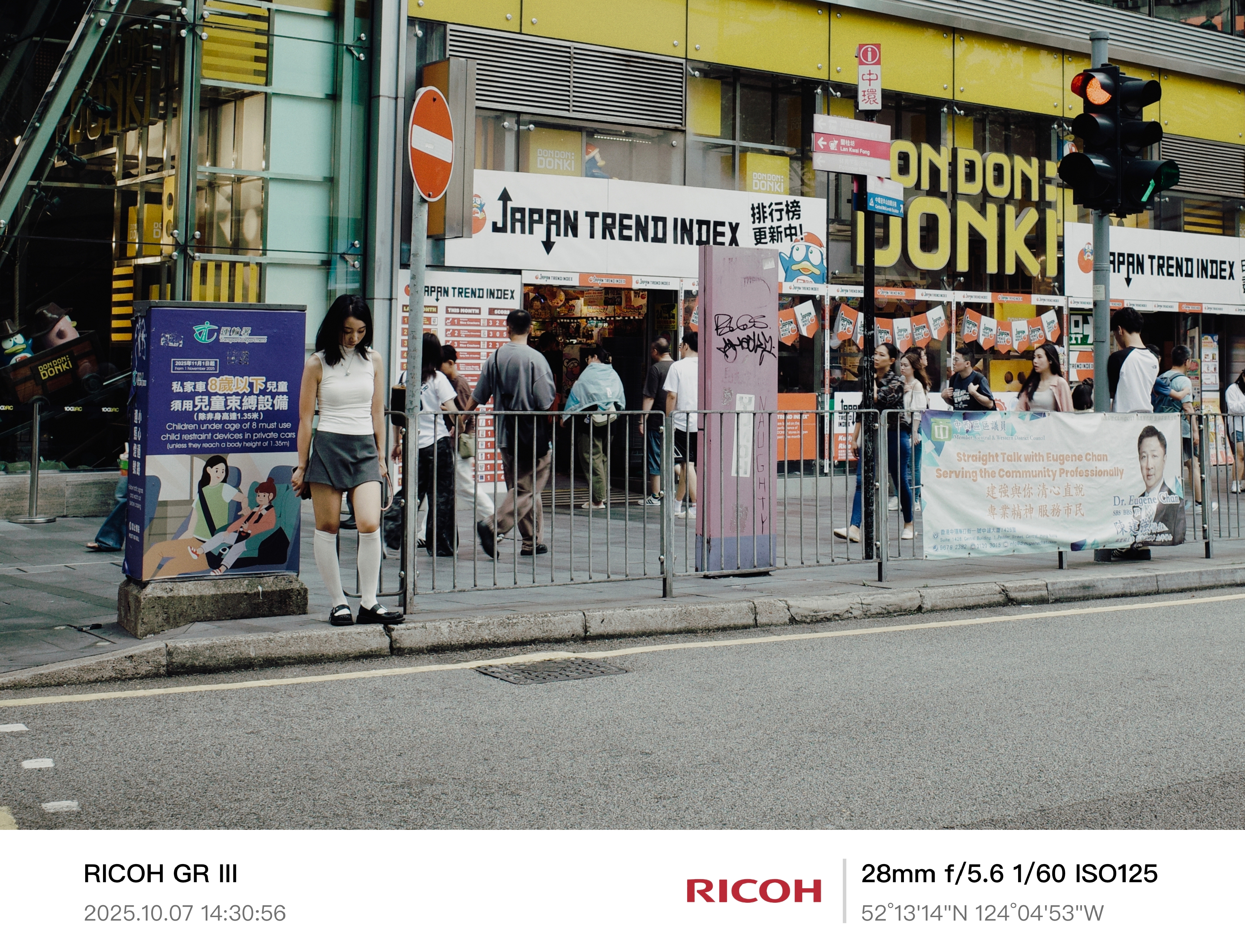 2025 - City in Motion - HK
《No Entry》
她低头站在禁止通行的标志下。
身后是拥挤的商场与快速流动的人群。
她没有动，世界便就此停止。